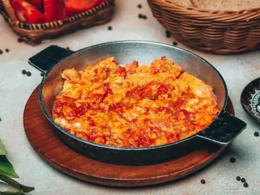 Uova strapazzate al pomodoro in padella, un piatto caldo e saporito, pronto per essere gustato.