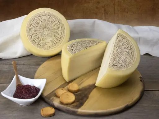 Formaggio Pecorella, un pecorino in gravidanza, servito con marmellata e taralli su un tagliere di legno.