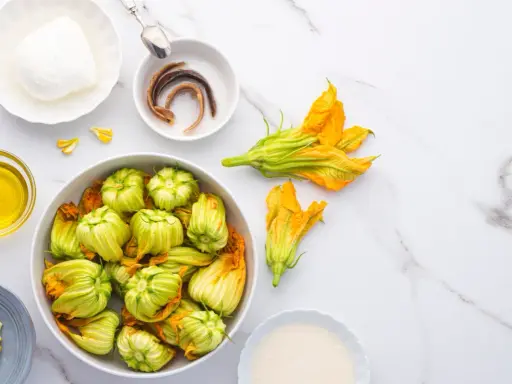 Fiori di zucca freschi, mozzarella, acciughe e olio d'oliva pronti per essere cucinati.