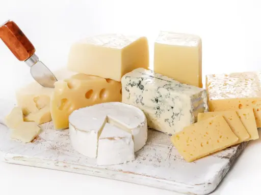 Varietà di formaggi senza lattosio: un pezzo di formaggio erborinato, un brie, formaggi a pasta dura e svizzero, pronti per essere gustati.