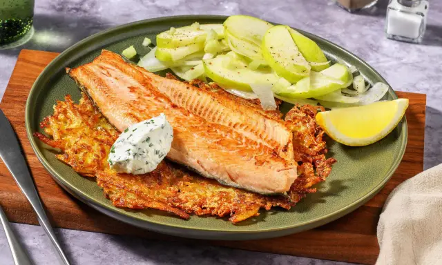 Filetto di salmone su croccanti rosti di patate, con insalata di mele e una quenelle di salsa alle erbe.