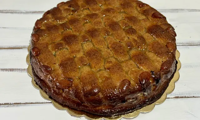 Deliziosa torta di mandorle siciliana, con una crosta dorata e mandorle intere che ne decorano il bordo.