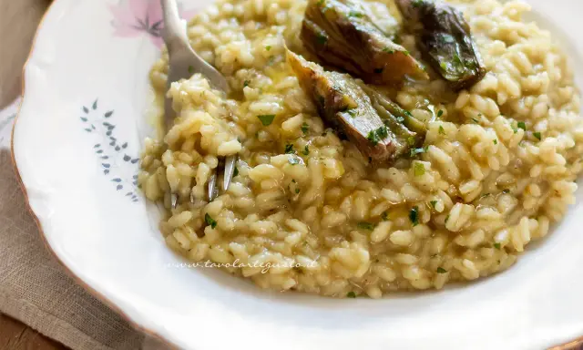 Un cremoso risotto con carciofi freschi, guarnito con prezzemolo tritato e un filo d'olio.
