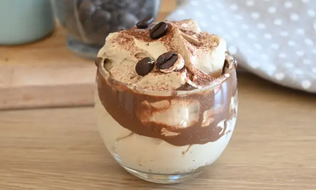 Deliziosa crema al caffè veloce in un bicchiere, guarnita con chicchi di caffè e cacao.