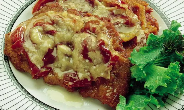 Cotoletta alla bolognese ricoperta di sugo e formaggio fuso, servita con insalata fresca su un piatto decorato.
