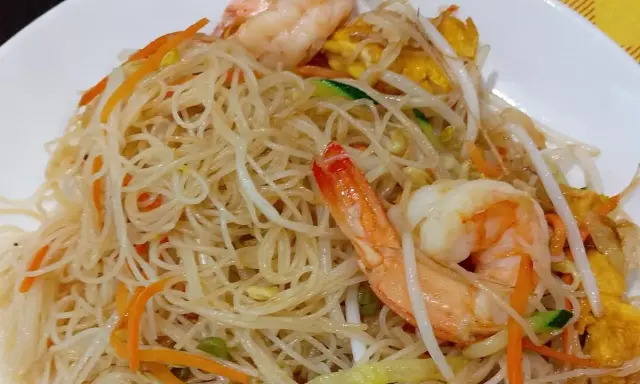 Spaghetti di riso con gamberi, carote, zucchine e germogli di soia. Un piatto leggero e gustoso.