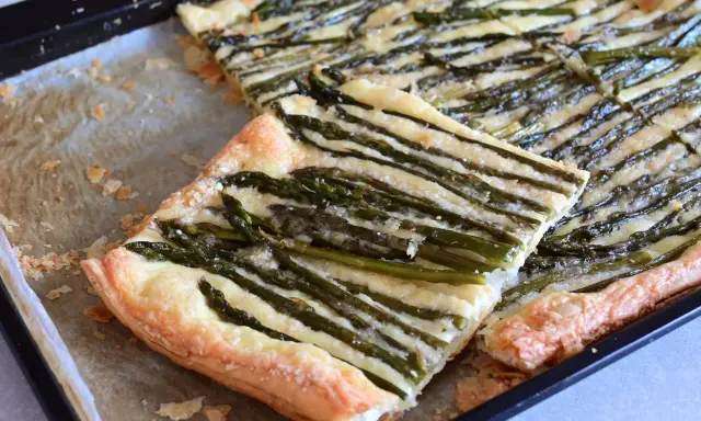 Deliziosa pasta sfoglia con asparagi e formaggio filante, appena sfornata su una teglia.