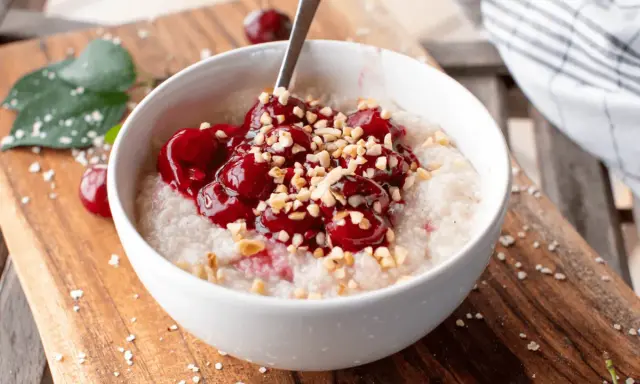 Una ciotola di porridge con ciliegie e nocciole tritate, una deliziosa colazione senza zuccheri.