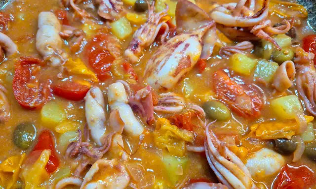 Totani in umido con pomodoro, patate e olive, un piatto saporito e colorato, pronto per essere gustato.