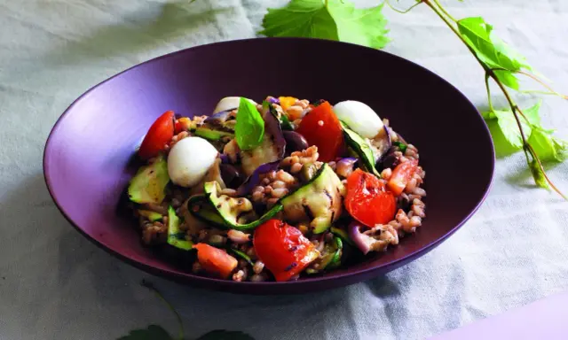 Insalata di farro estiva con verdure grigliate, pomodorini, mozzarelline e basilico, un piatto fresco e colorato.