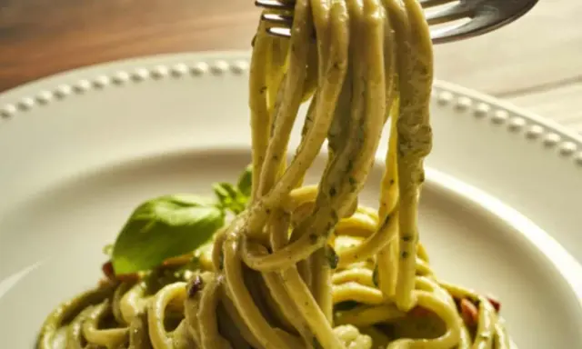 Trenette al pesto, un piatto invitante con pasta fresca avvolta in una salsa verde vibrante, guarnito con basilico.