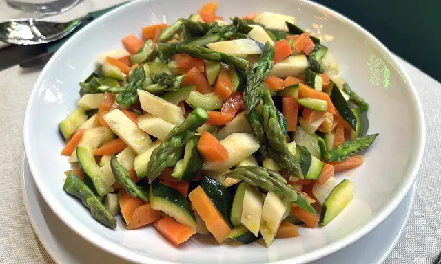 Un piatto invitante di verdure in padella: carote, zucchine e asparagi tagliati a pezzetti, cotti al punto giusto per un contorno sano e colorato.