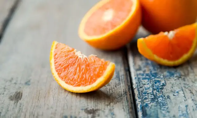 Arance fresche tagliate a spicchi su un tavolo di legno. Quante arance si possono mangiare al giorno? Dipende dal tuo fabbisogno di vitamina C.