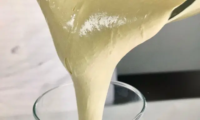 Versando una soffice pate a bombe in un bicchiere trasparente, pronta per una deliziosa preparazione.