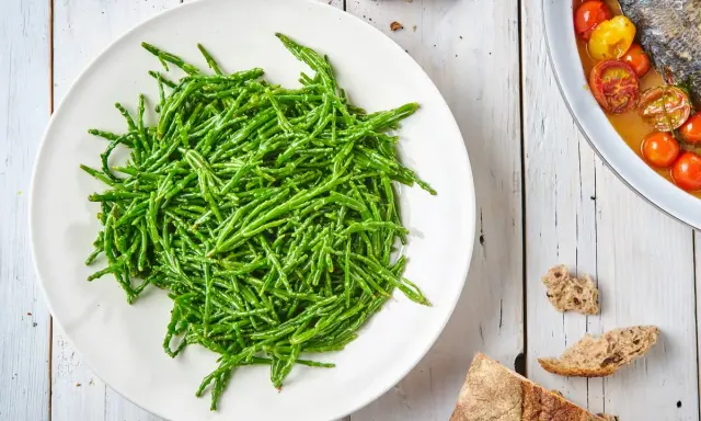 Piatto bianco colmo di asparagi di mare freschi e croccanti, pronti per essere gustati.