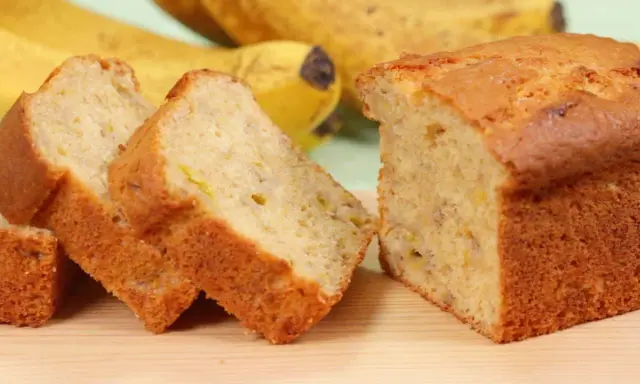 Fette di banana bread light, soffice e dorato, con banane mature sullo sfondo.
