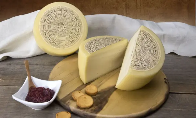 Formaggio Pecorella, un pecorino in gravidanza, servito con marmellata e taralli su un tagliere di legno.