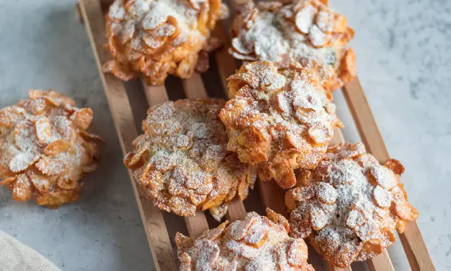 Dolci croccanti, simili a rose del deserto, ricoperti di fiocchi di mais e spolverati di zucchero a velo.