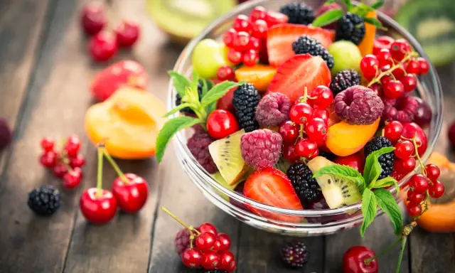Ciotola di frutta fresca con fragole, lamponi, ribes, more e kiwi, un'ottima scelta di frutta con meno zuccheri.