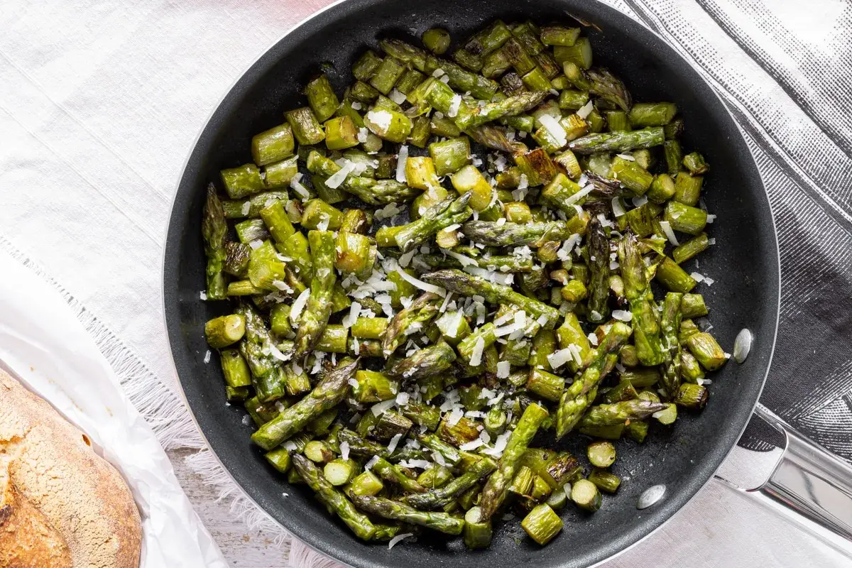 Asparagi in padella, saltati e cosparsi di parmigiano grattugiato, pronti per essere gustati.