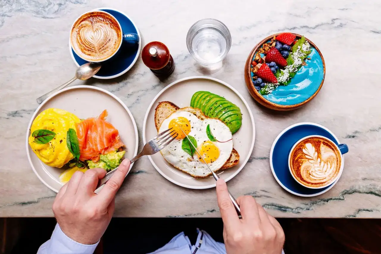 Esempi di colazione a basso indice glicemico: uova, salmone, avocado, smoothie bowl e caffè.