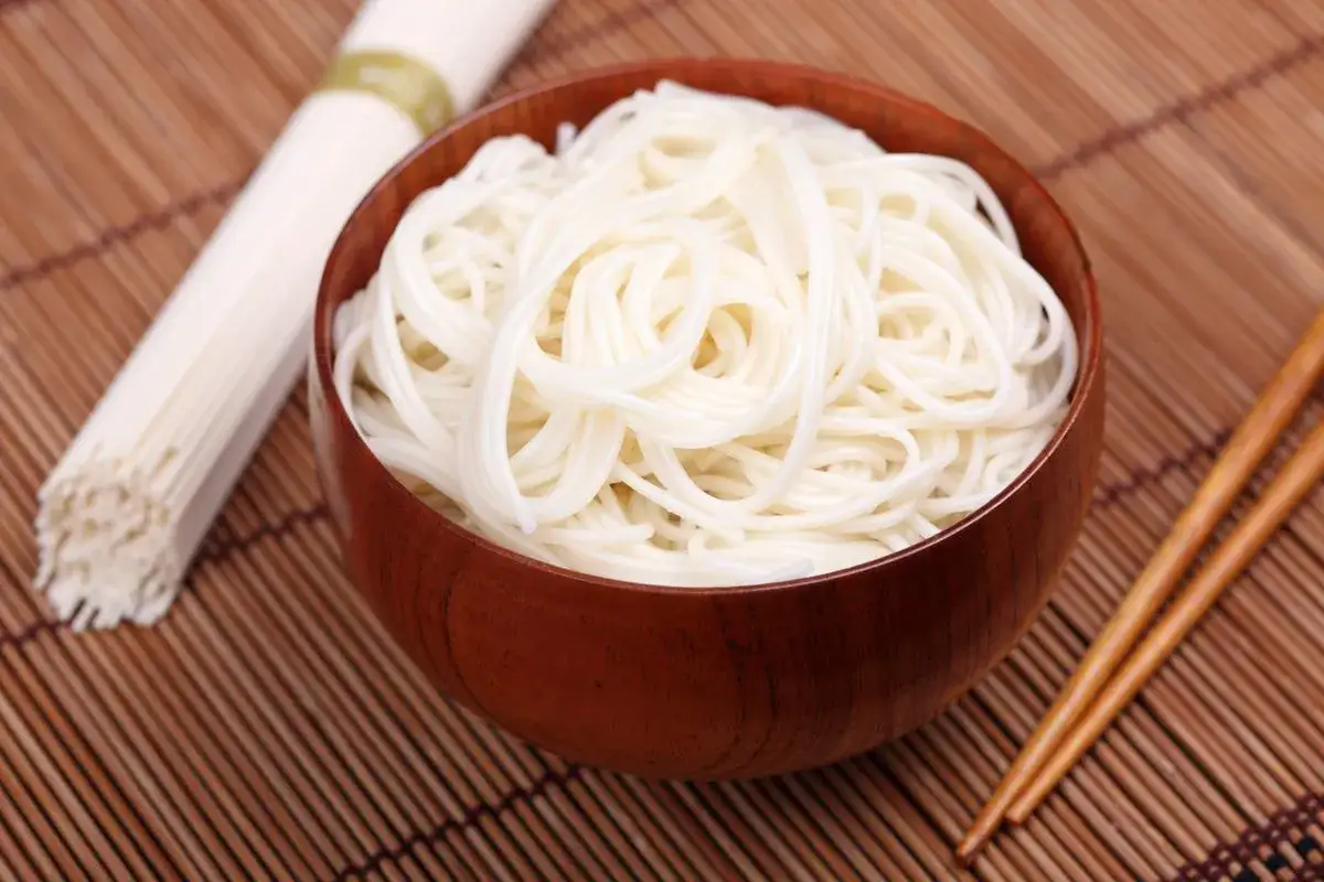 Una ciotola di spaghetti di riso bianchi e sottili, pronti per essere gustati con le bacchette.