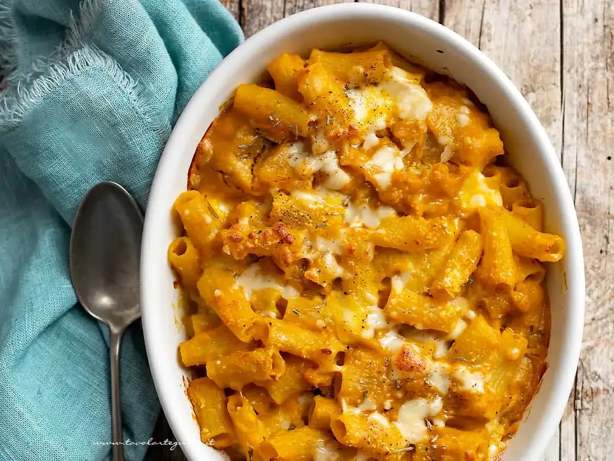 Un invitante piatto di pasta pasticciata al forno, con un sugo cremoso e formaggio filante, pronto per essere gustato.
