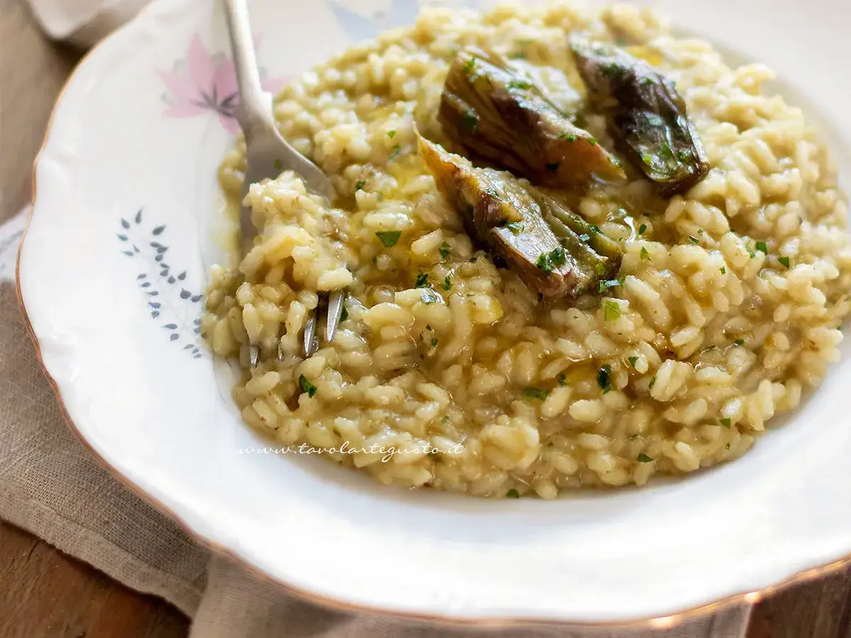 Un cremoso risotto con carciofi freschi, guarnito con prezzemolo tritato e un filo d'olio.