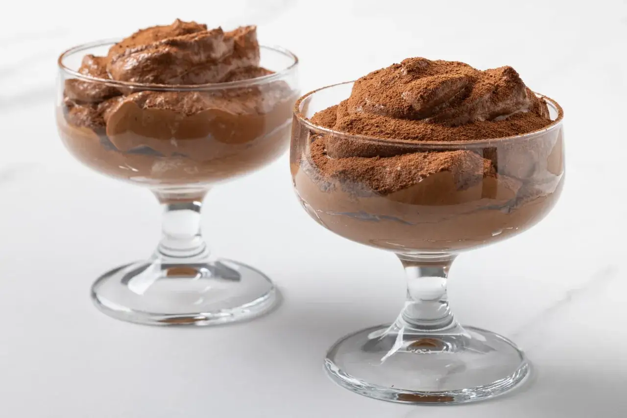 Due coppette di cremoso tiramisù senza caffè, spolverate di cacao amaro.