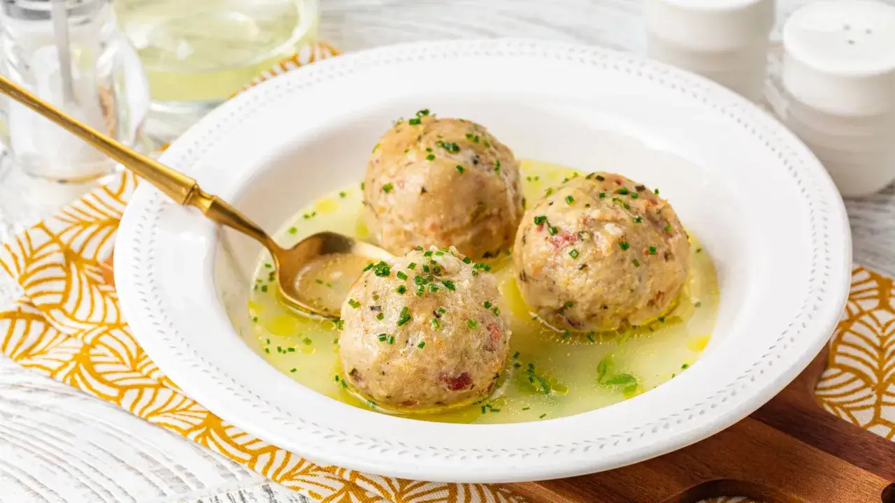 Tre canederli in brodo, un classico delle ricette con pane raffermo, guarniti con erba cipollina.