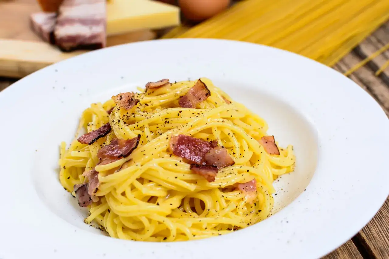 Un piatto di spaghetti alla carbonara, perfetto per la giornata della carbonara, con guanciale croccante e pepe nero.