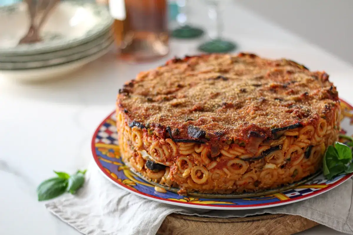 Anelletti al forno, un tortino di pasta dorato e invitante, con strati di melanzane e sugo, pronto per essere gustato.