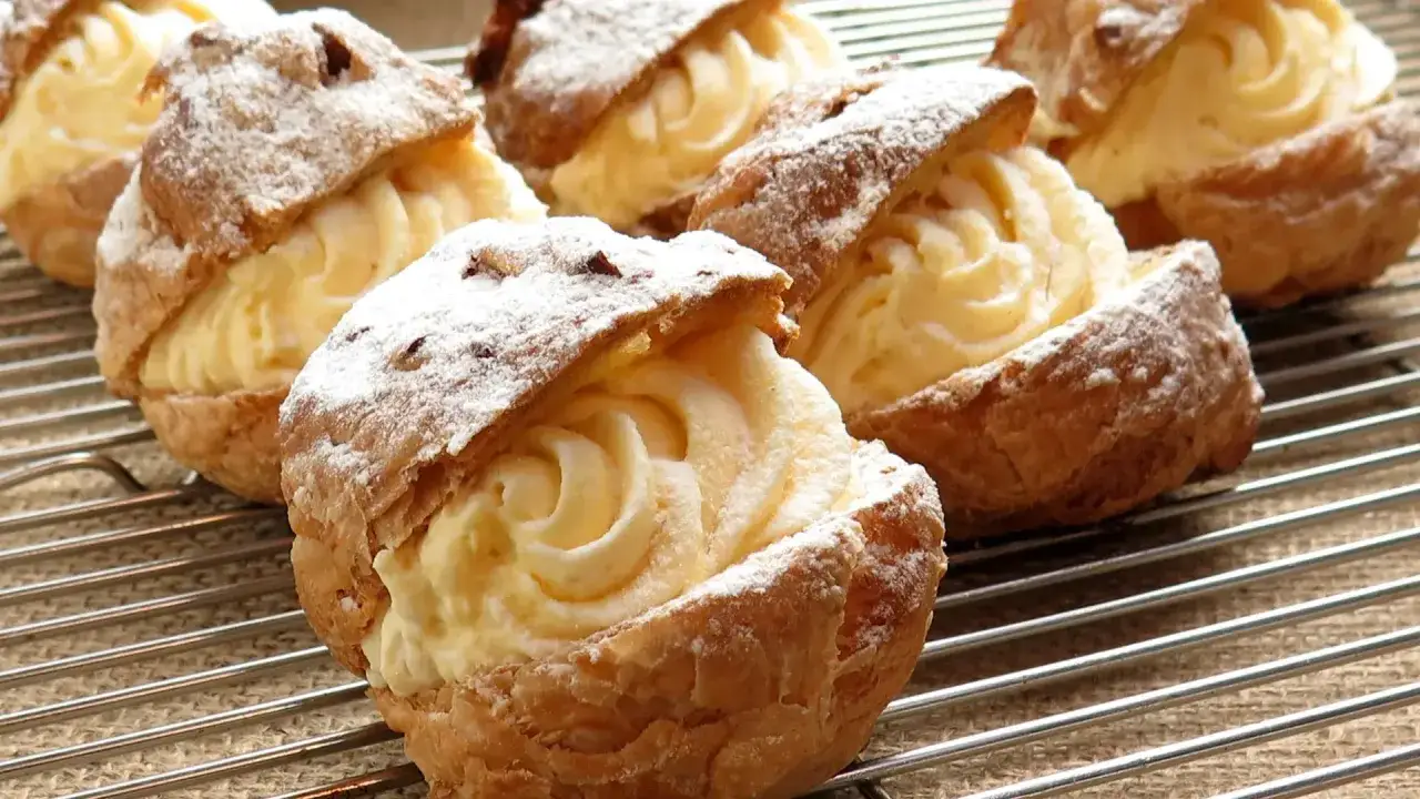 Bign&egrave; alla crema, dolci soffici e invitanti, con abbondante crema pasticcera e una spolverata di zucchero a velo.