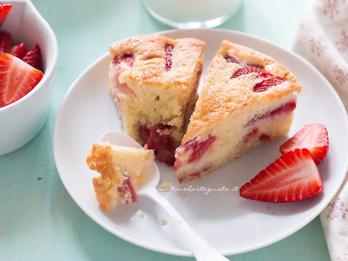 Fette di torta alle fragole su un piatto bianco, con fragole fresche a lato e un cucchiaino con una briciola.