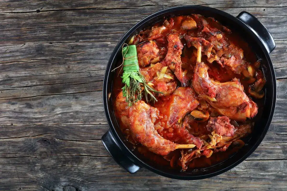 Coniglio in padella, succulento e profumato, cotto lentamente con pomodoro e erbe aromatiche.
