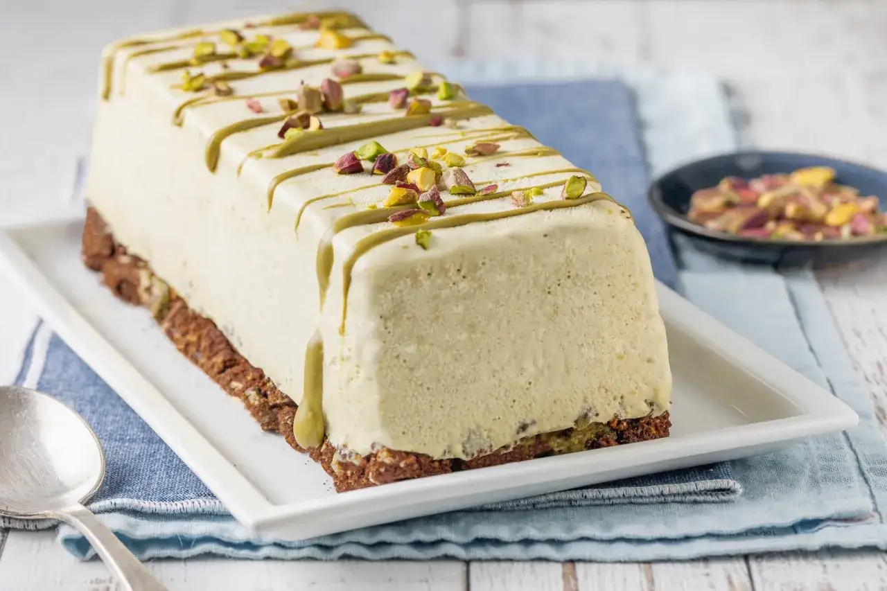 Delizioso semifreddo al pistacchio con glassa verde e granella di pistacchi, su base croccante.