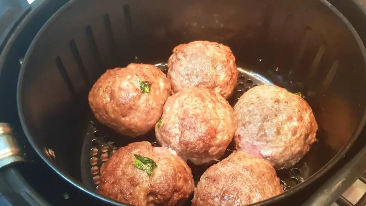 Sei polpette dorate e succulente cuociono nella friggitrice ad aria, pronte per essere gustate.