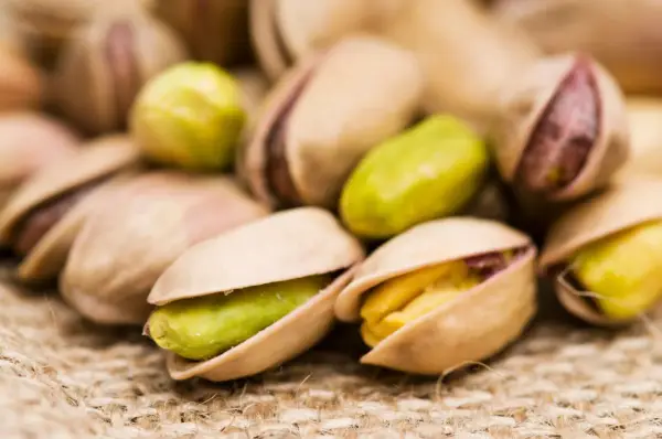 Un mucchio di pistacchi, alcuni aperti rivelano il loro interno verde e giallo. Attenzione, i pistacchi fanno ingrassare!