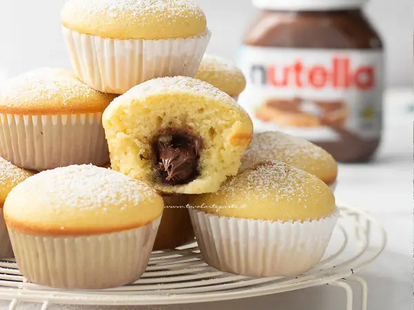 Muffin semplici con cuore morbido di Nutella, spolverati di zucchero a velo. Una ricetta golosa e facile da preparare.